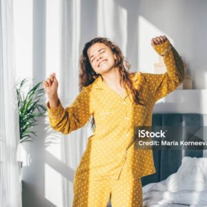 Woman in yellow pyjamas dancing in morning at home.